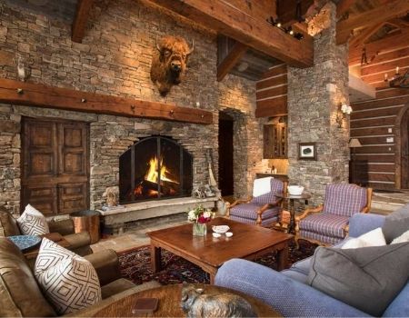 Mountain home living room with large stone fireplace and buffalo head.